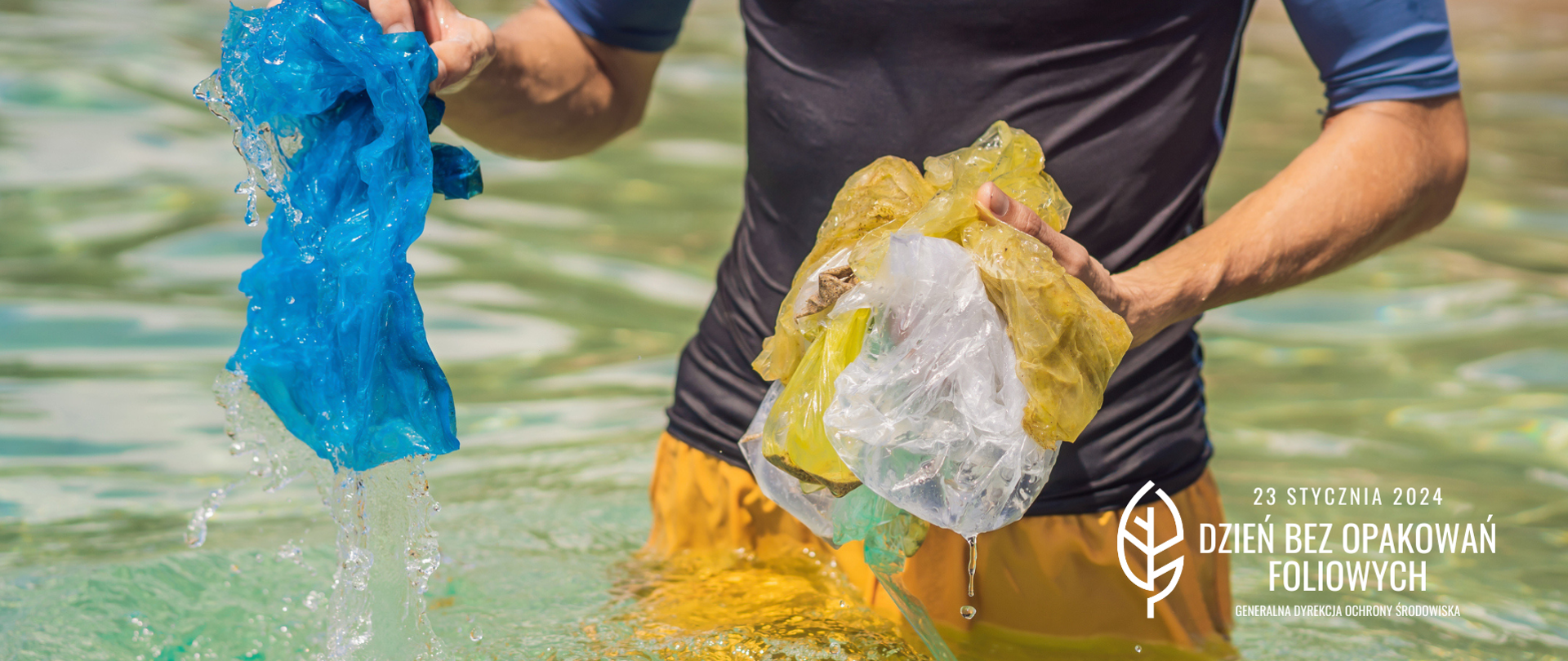 Mężczyzna w sportowym stroju stoi po biodra w wodzie,. W rękach trzyma ociekające woda foliowe woreczki, które wyjął z wody.