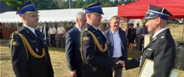Zastępca Komendanta Wojewódzkiego PSP ściska rękę Prezesa OSP trzymającego w drugim ręku akt włączenia do KSRG