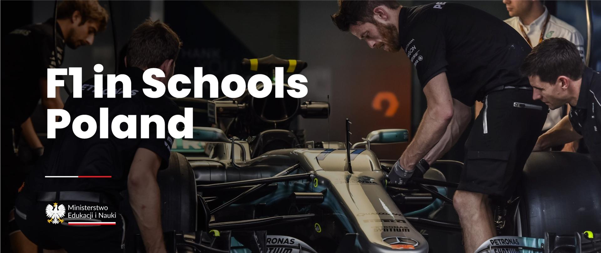 Bolid formuły 1, a przy nim pracujący mężczyźni oraz napis F1 in Schools Poland