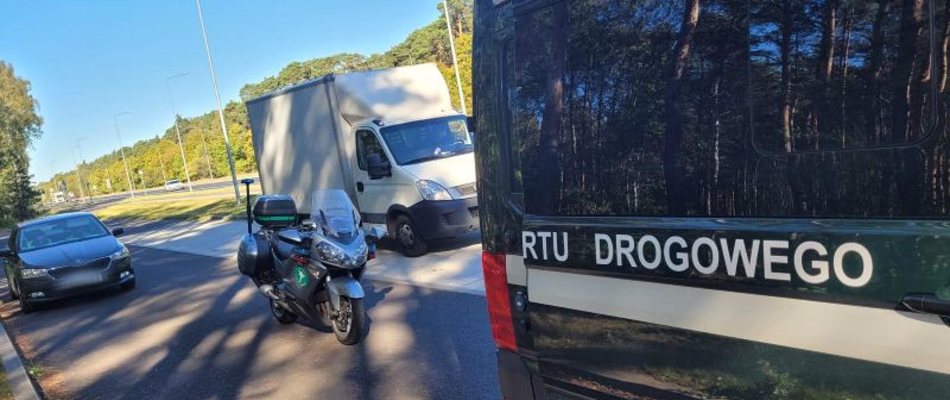 Widok pojazdów służbowych na tle kontrolowanego pojazdu ciężarowego 