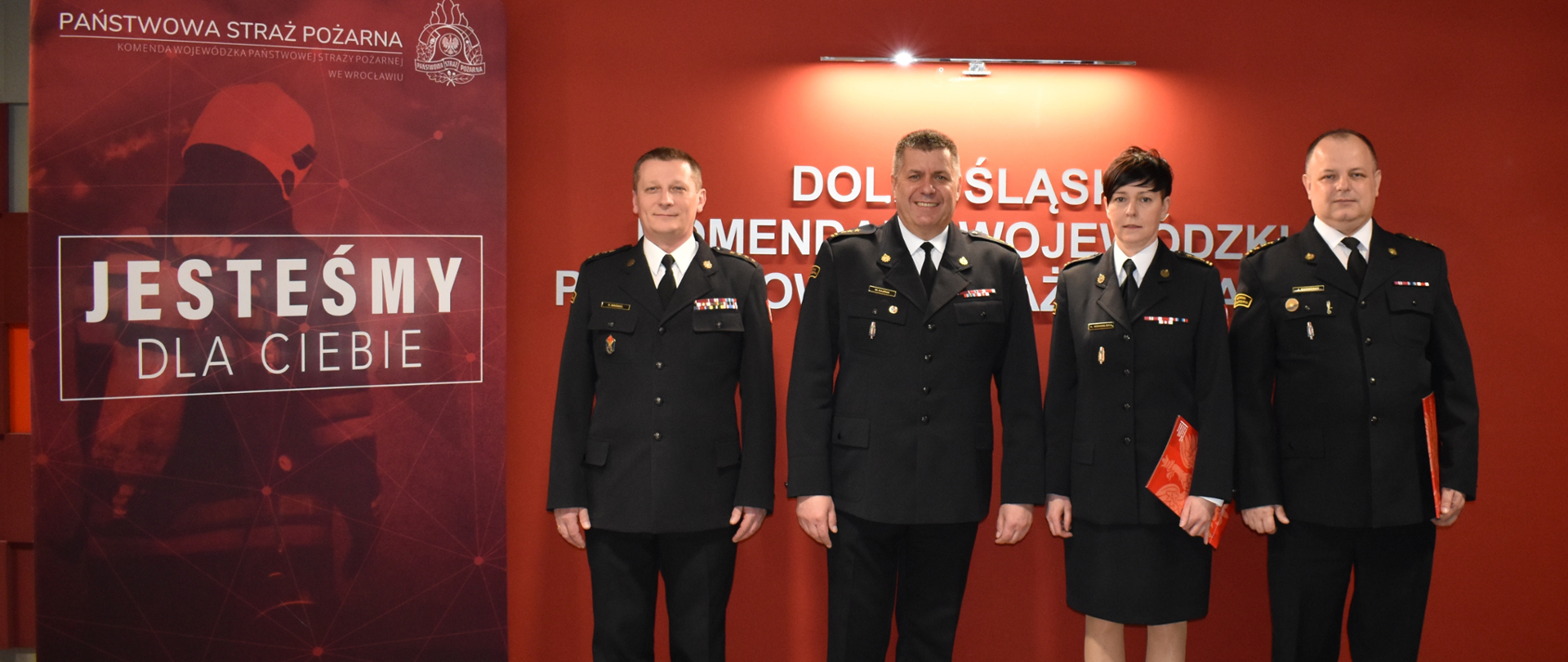 Osoby w mundurach pozujące do zdjęcia na tle ściany.