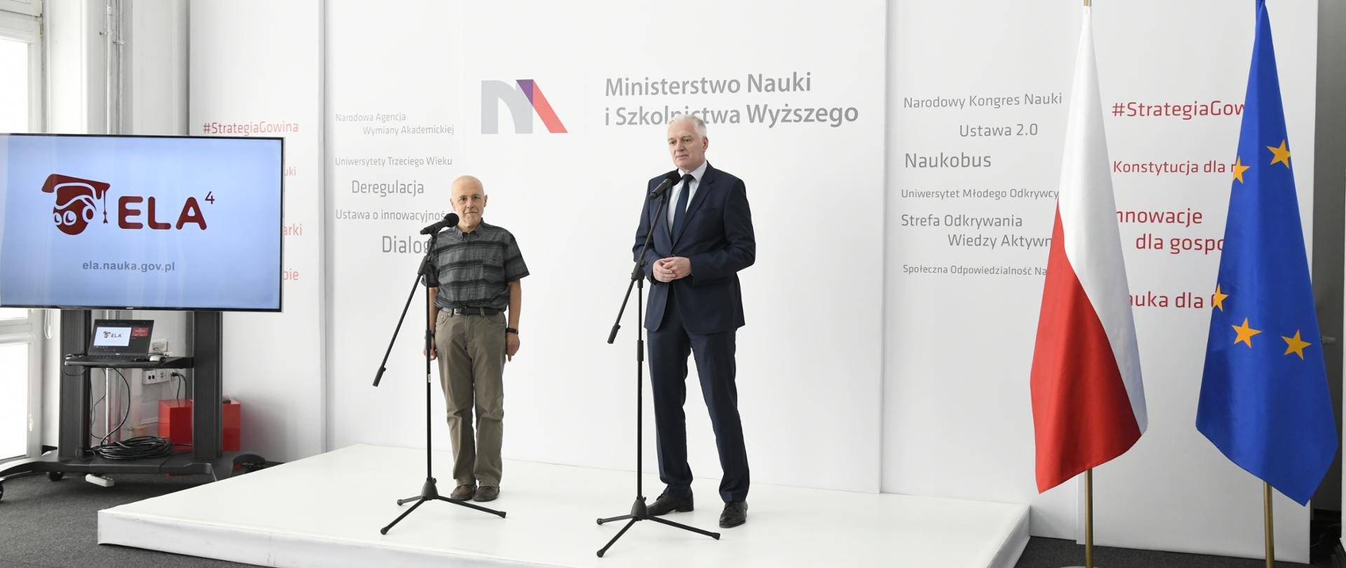 Na scenie przy mikrofonach stoi prof. M. Jasiński i wicepremier Jarosław Gowin. Na ekranie prezentacja multimedialna poświęcona systemowi ELA.