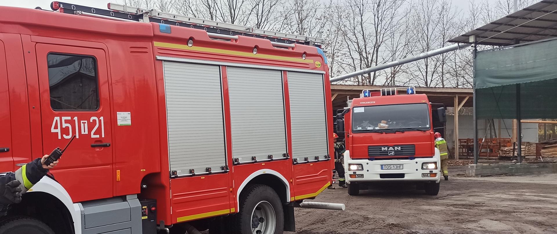Na zdjęciu w porze dziennej widać dwa samochody gaśnicze manewrujące na placu tartaku.