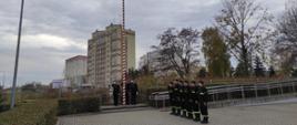 Zdjęcie przedstawia strażaków podczas uroczystego wciągnięcia flagi na masz w celu uczczenia kolejnej rocznicy odzyskania przez Polskę Niepodległości. 