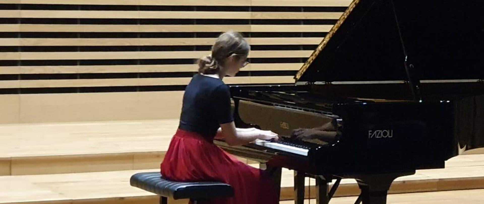 Nastolatka na estradzie sali koncertowej gra na fortepianie - zbliżenie.