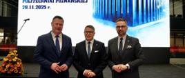 Na tle wielkiego ekranu z granatowym napisem na białym tle Otwarcie nowego rektoratu Politechniki Poznańskiej 28.11.2025. stoi minister Kulasek i dwóch mężczyzn w garniturach.