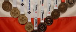 Zdjęcie przedstawia 10 medali eksponowanych na fladze Polski.