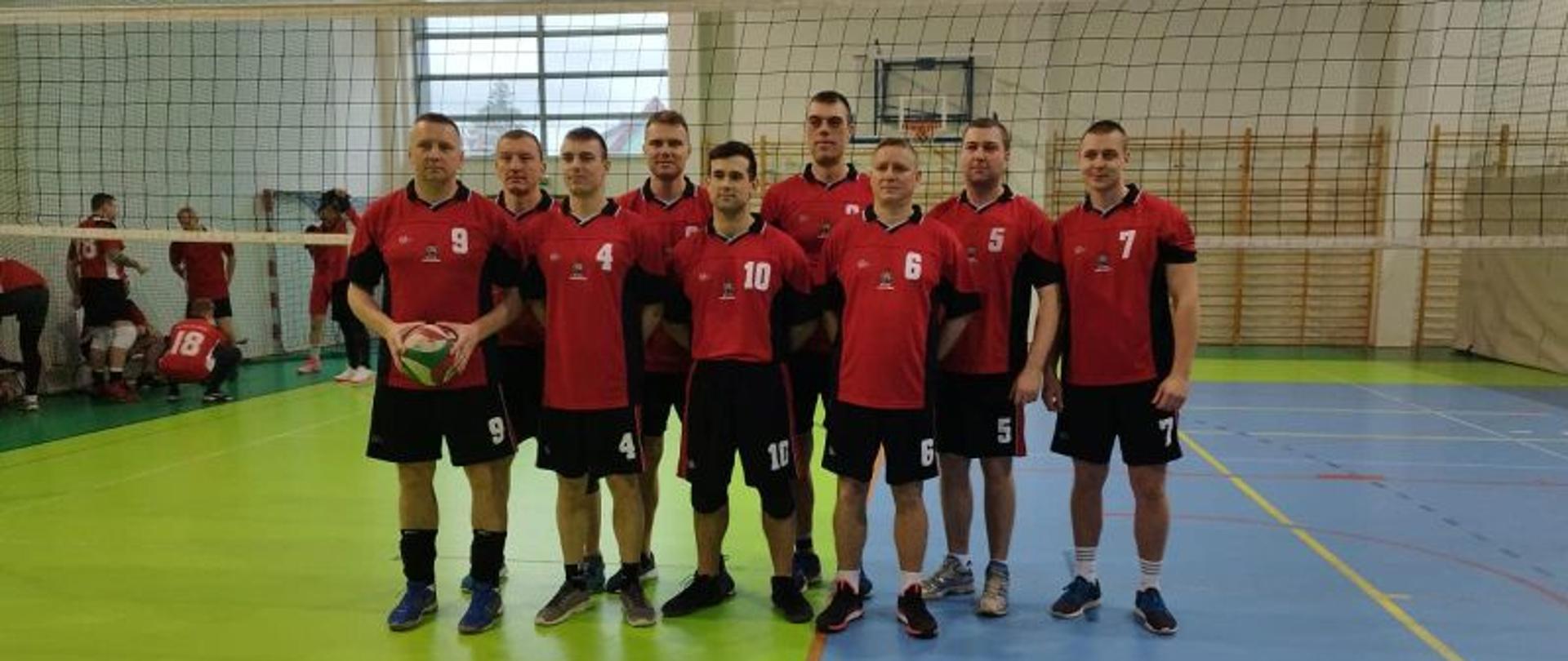 Zdjęcie grupowe przedstawiające drużynę KP PSP Białogard. Strażacy stoją na środku Sali w sportowych strojach.