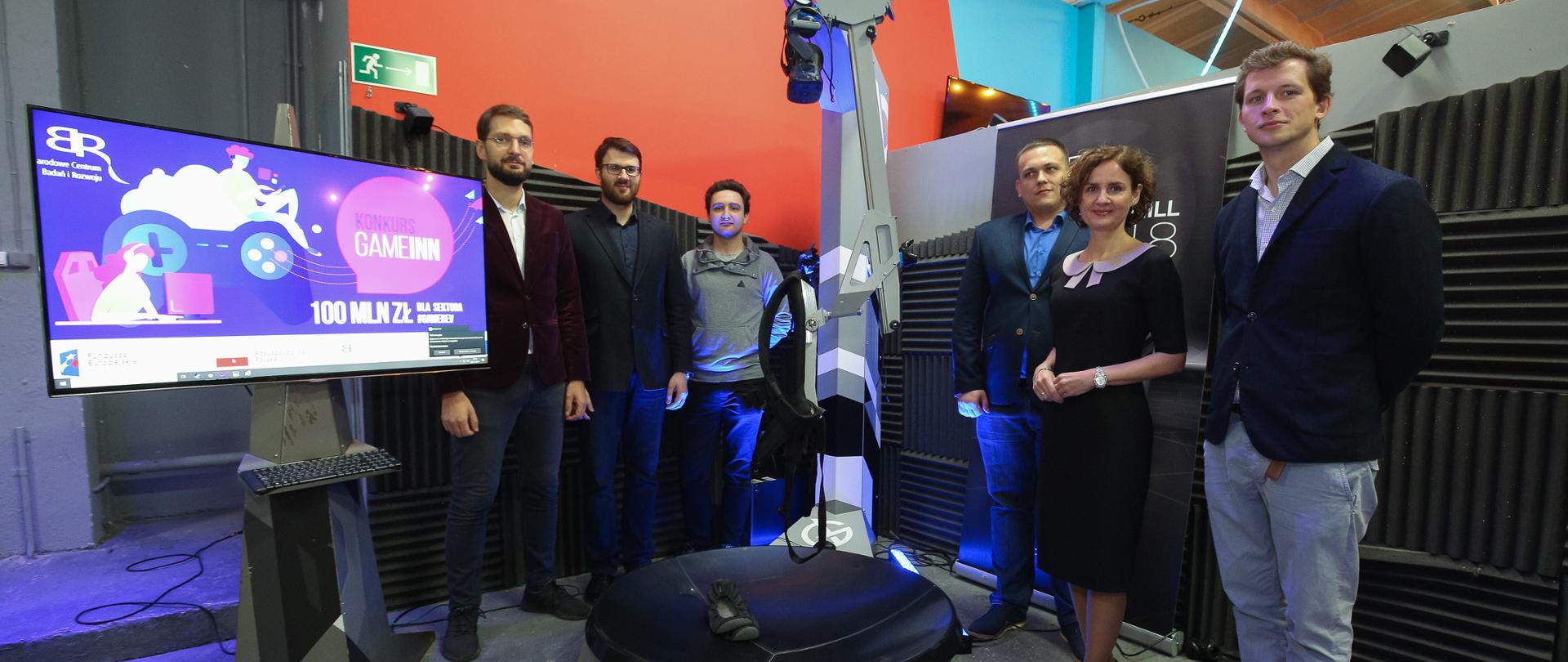 Przy robocie stoją laureaci programu GameInn