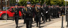 Pododdział strażaków maszeruje na Plac Wolności w Nidzicy - prowadzi st.kpt. Nikodem Woźniak