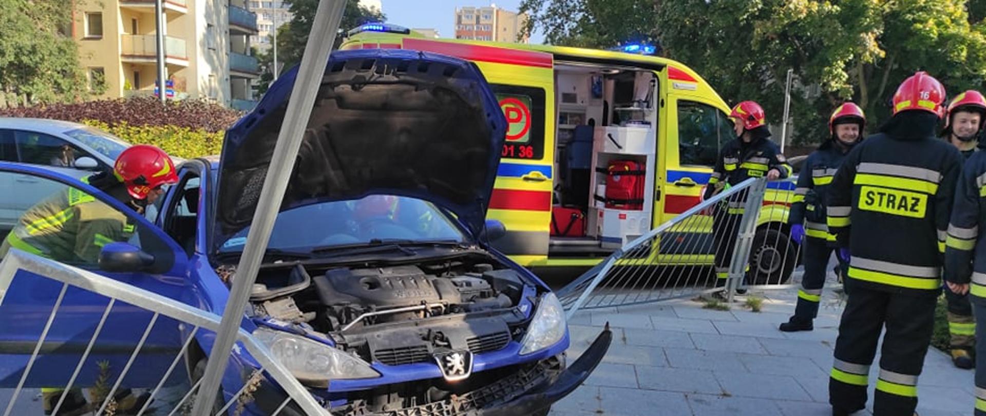 Na zdjęciu widoczny jest samochód osobowy który brał udział w wypadku, pracujący strażacy oraz karetka pogotowia