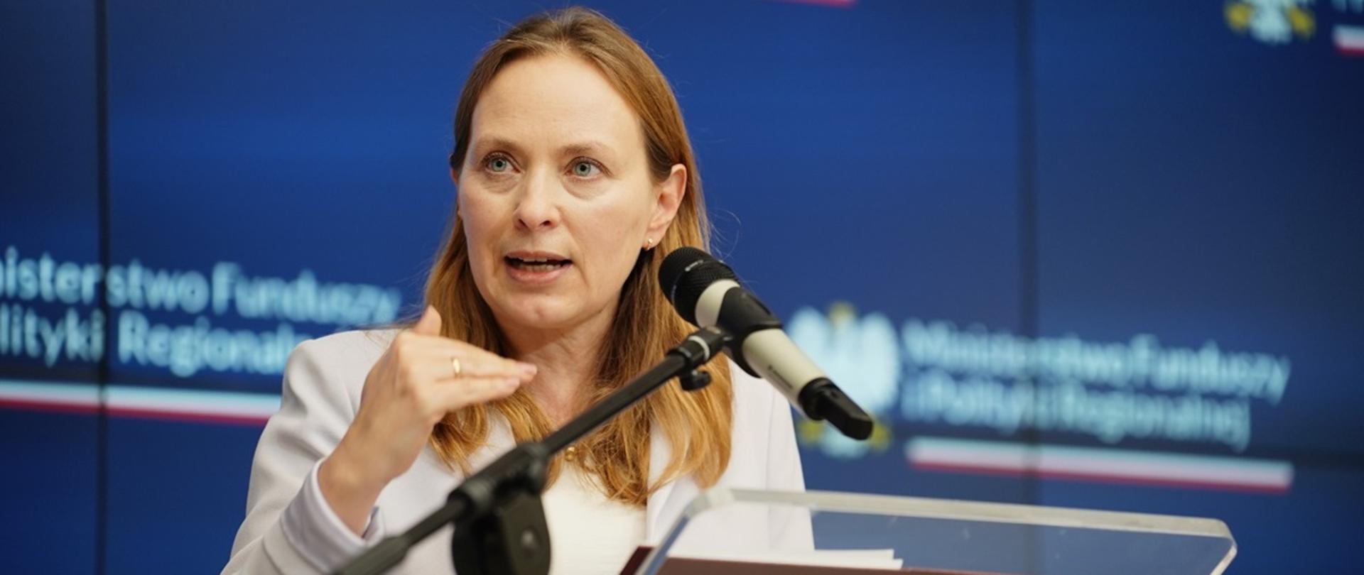 Minister funduszy i polityki regionalnej Katarzyna Pełczyńska-Nałęcz stoi przy mównicy i przemawia do mikrofonu