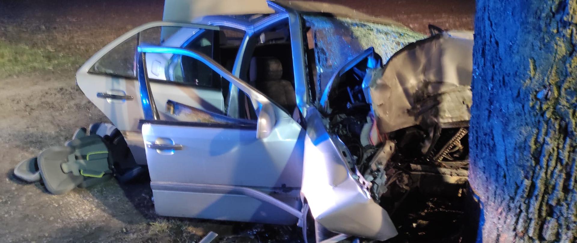 Rozbity samochód osobowy koloru srebrnego po uderzeniu w drzewo