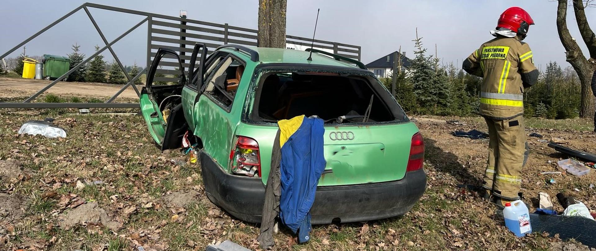 Zdjęcie przedstawia uszkodzone Audi oraz strażaka PSP