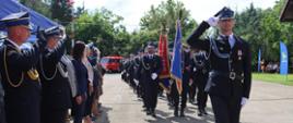 Przed trybuną honorową maszerują druhowie z kompanii honorowej i pocztów szatandarowych OSP.