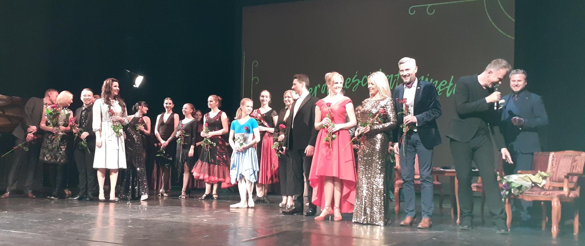 Zdjęcie pokazuje byłych i obecnych uczniów stojących na scenie.