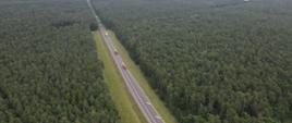 Na zdjęciu widoczna jest droga biegnąca wzdłuż lasu.