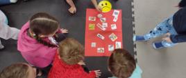 dzieci układają obrazki z niezdrowymi przekąskami na czerwonej planszy