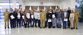 Grupowe zdjęcie uczestników szkolenia (27 osób) w towarzystwie Zastępcy Komendanta Centralnej Szkoły PSP, kobiety oraz dwóch funkcjonariuszy CS PSP