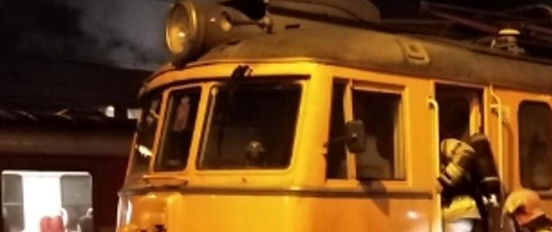Fotografia przedstawia strażaków wchodzących do palącej się w środku lokomotywy.