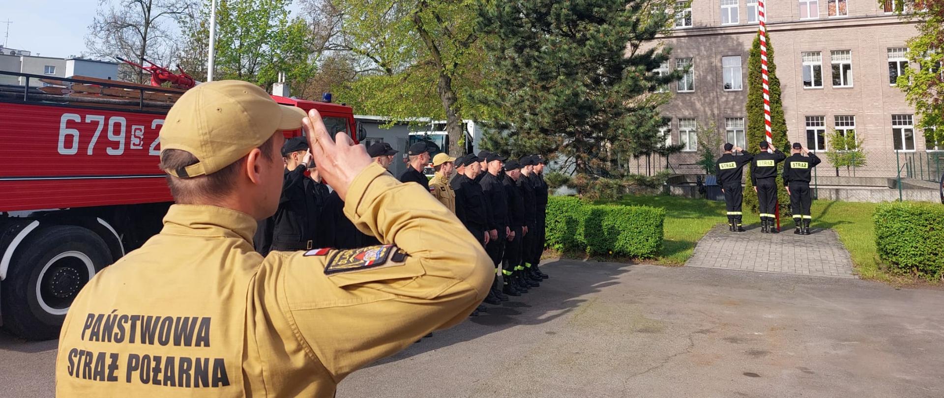Strażacy w trakcie uroczystego podniesienia flagi państwowej na maszt.