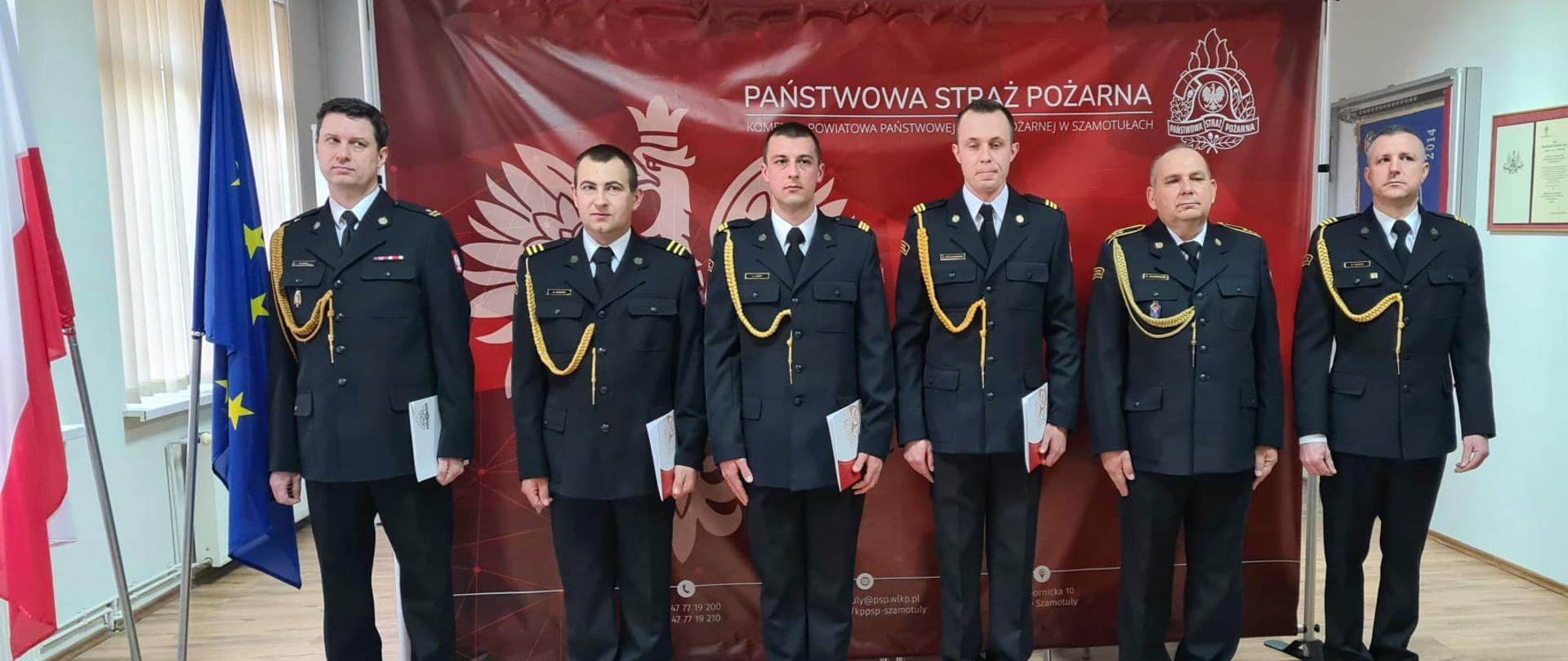 Awansowani strażacy na tle baneru PSP