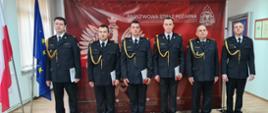 Awansowani strażacy na tle baneru PSP