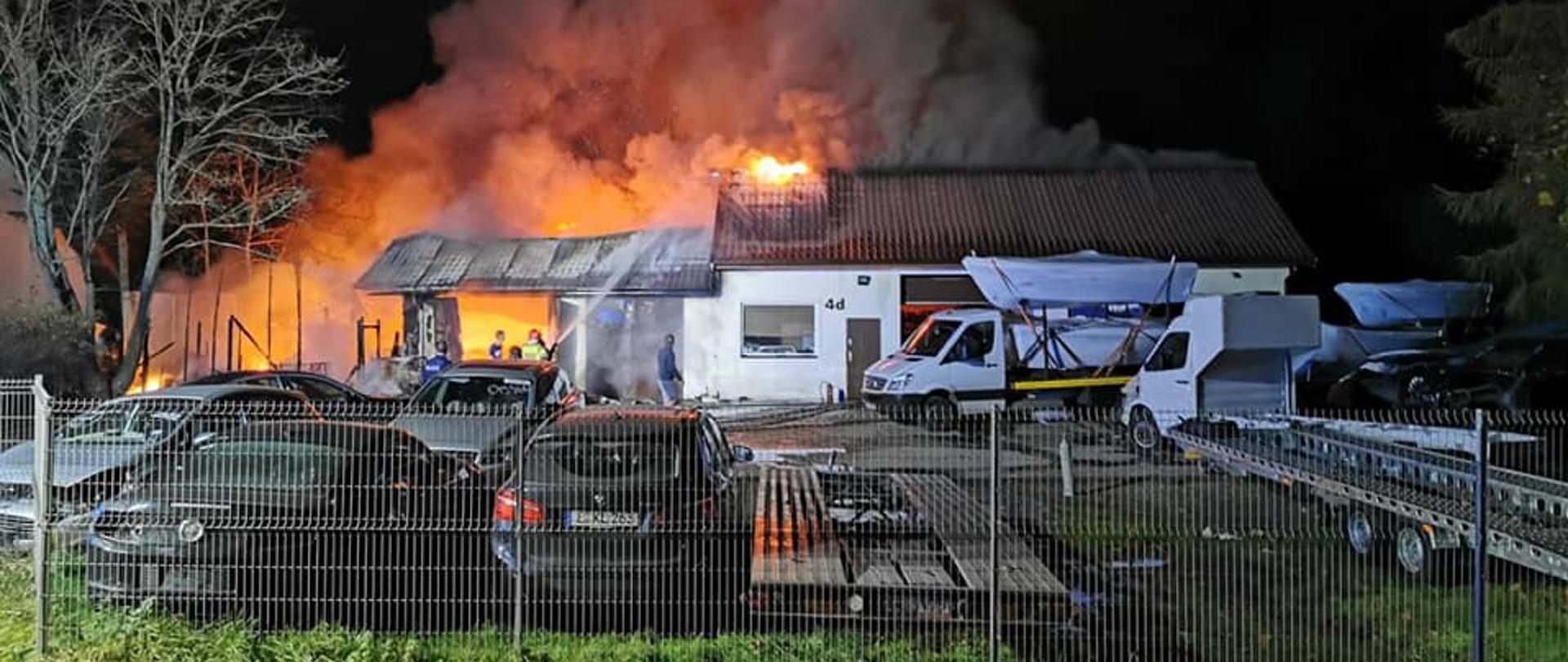 Zdjęcie przedstawia pożar budynku mieszkalnego wraz z garażami.