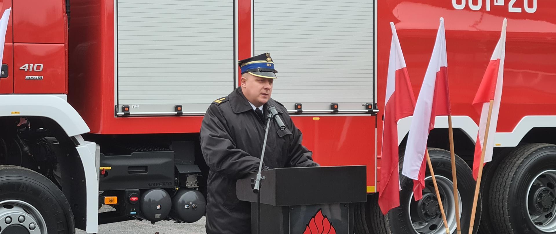 Na zdjęciu Komendant powiatowy bryg. Jarosław Kołak w tle samochód strażacki