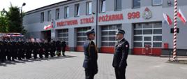 Dowódca uroczystości składa meldunek o gotowości do rozpoczęcia uroczystości Mazowieckiemu Komendantowi Wojewódzkiemu PSP, w oddali z lewej strony pododdział strażaków, na tle budynku Komendy