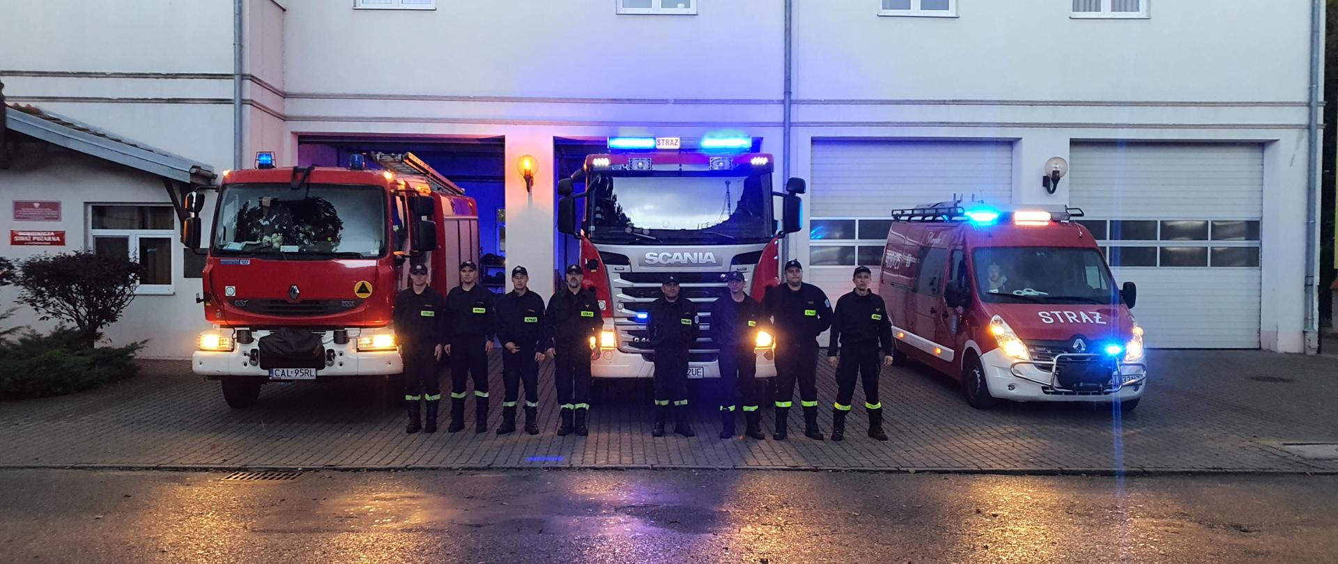 Zdjęcie przedstawia strażaków PSP i OSP zebranych na placu przed JRG w Ciechocinku podczas zbiórki dot. Minuty ciszy poległym strażakom OSP. na drugim planie zdjęcia samochody strażackie w włączonymi sygnałami świetlnymi a tle budynek JRG