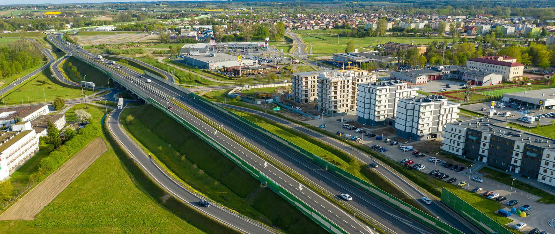 S7 obwodnica Płońska, węzeł Płońsk Centrum, widać pojazdy na drodze i bliską zabudowę miasta