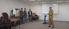 Zdjęcie przedstawia funkcjonariusza PSP i czterech prelegentów w sali narad