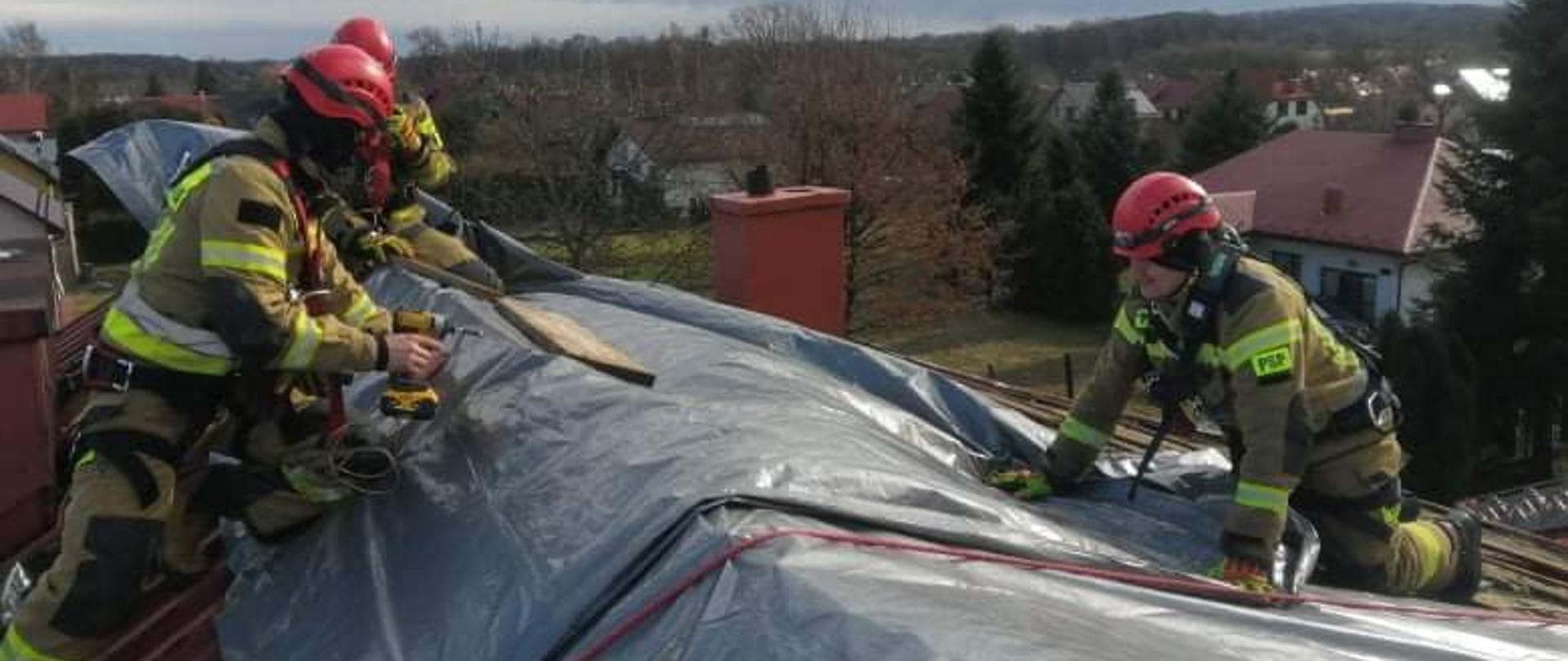 Strażacy na dachu w trakcie zabezpieczania dachu