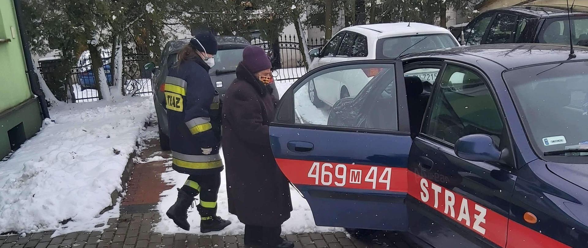 strażacy OSP pomagają seniorowi w transporcie na szczepienie. wejście do samochodu strażackiego