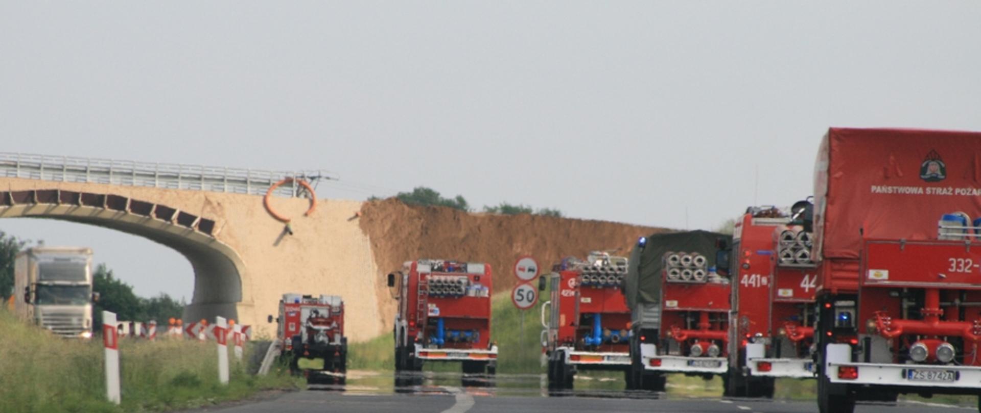 Zdjęcie przedstawia kolumnę samochodów pożarniczych