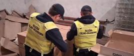 Funkcjonariusze Służby Celno-Skarbowej podczas inspekcji zawartości kartonów.