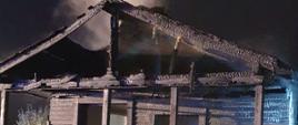 Widok na front drewnianego budynku po pożarze. Z dachu unosi się para wodna.