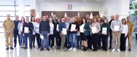Pamiątkowe zdjęcie grupowe uczestników szkolenia inspektorów ochrony przeciwpożarowej (29 osób) w towarzystwie kobiety oraz dwóch oficerów CS PSP