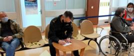 Zastępca pomorskiego komendanta wojewódzkiego PSP wypełnia dokumenty przed szczepieniem.