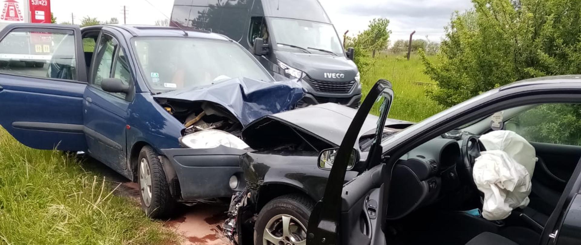 dwa samochody zderzone czołowo, w tle bus i samochód pożarniczy