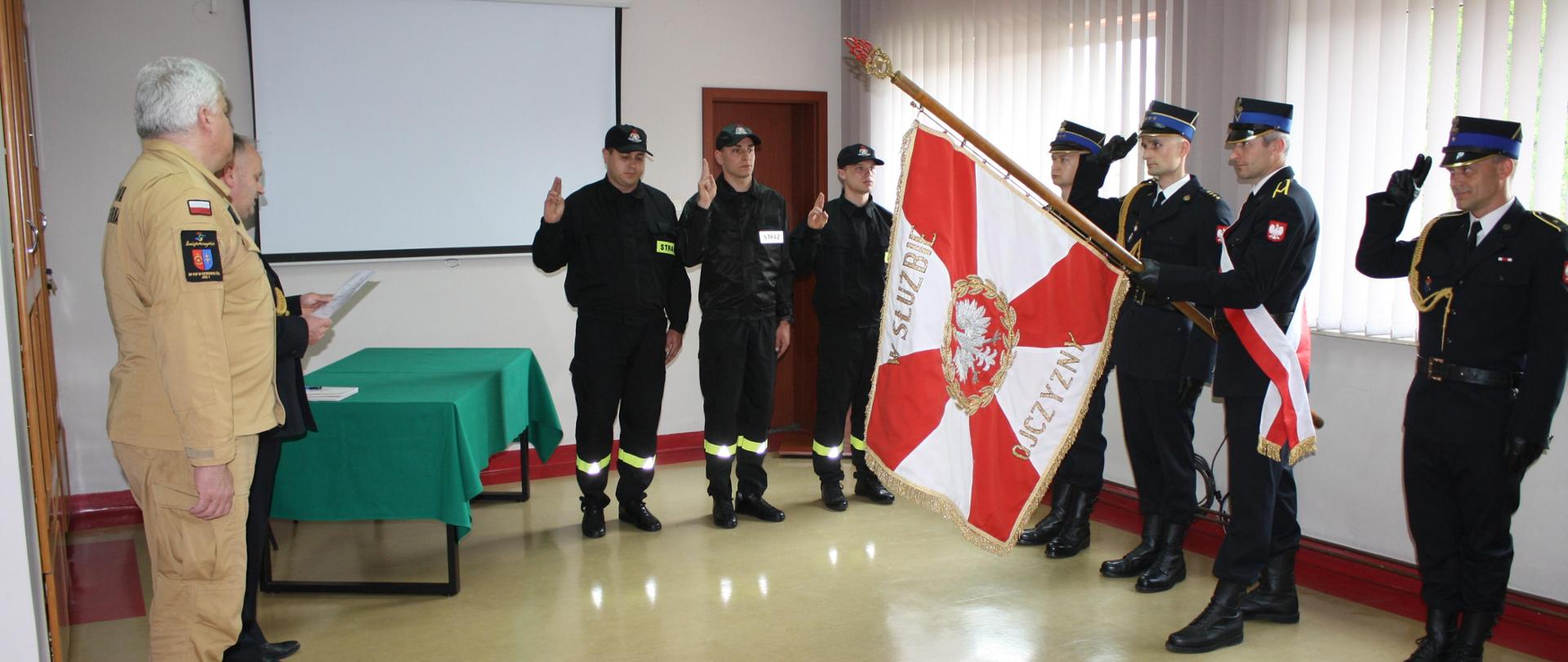Strażacy oddający gest ślubowania do sztandaru KP PSP w Starachowicach