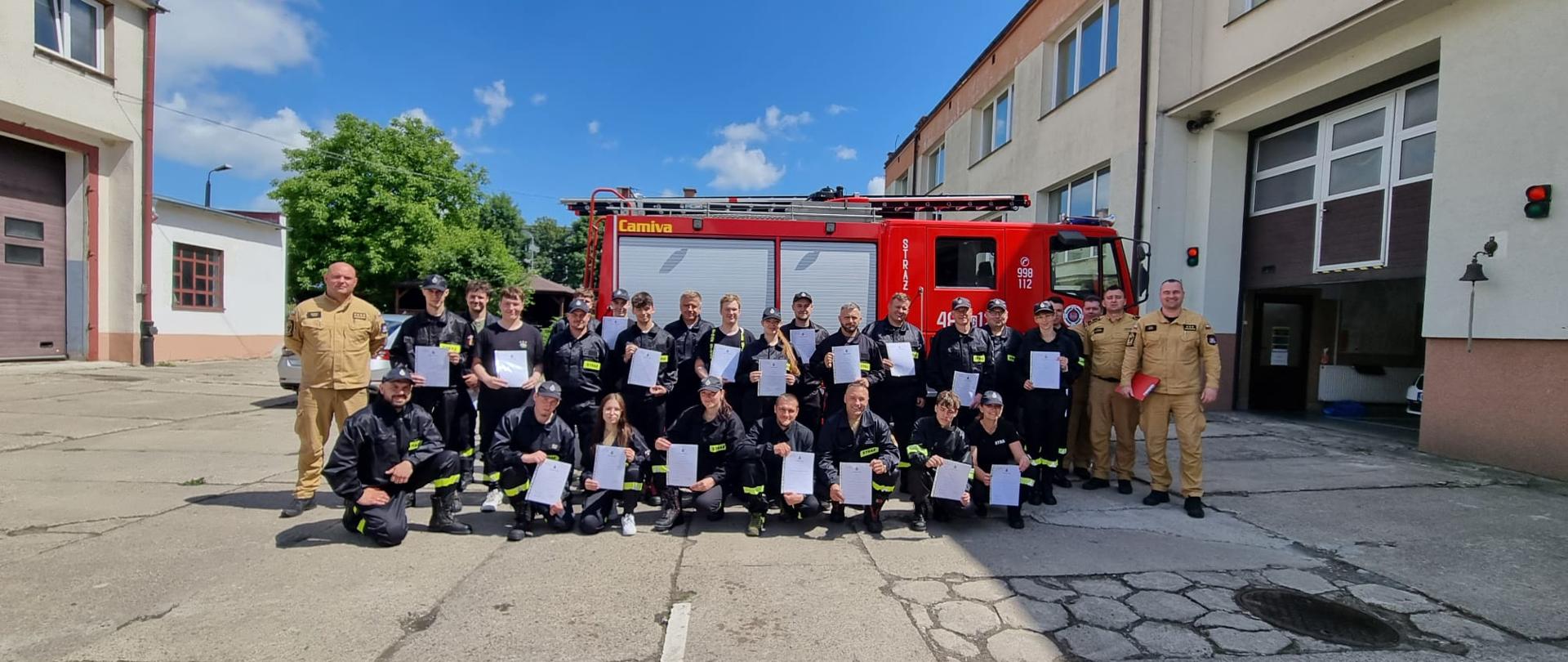Zdjęcie grupowe na tle samochodu strażackiego absolwentów kursu podstawowego OSP.