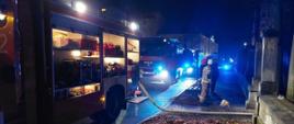 Na zdjęciu widać 3 samochody ratowniczo – gaśnicze podczas działań przy szpitalu im. E. Szczeklika oraz dwóch strażaków stojących obok linii wężowej.