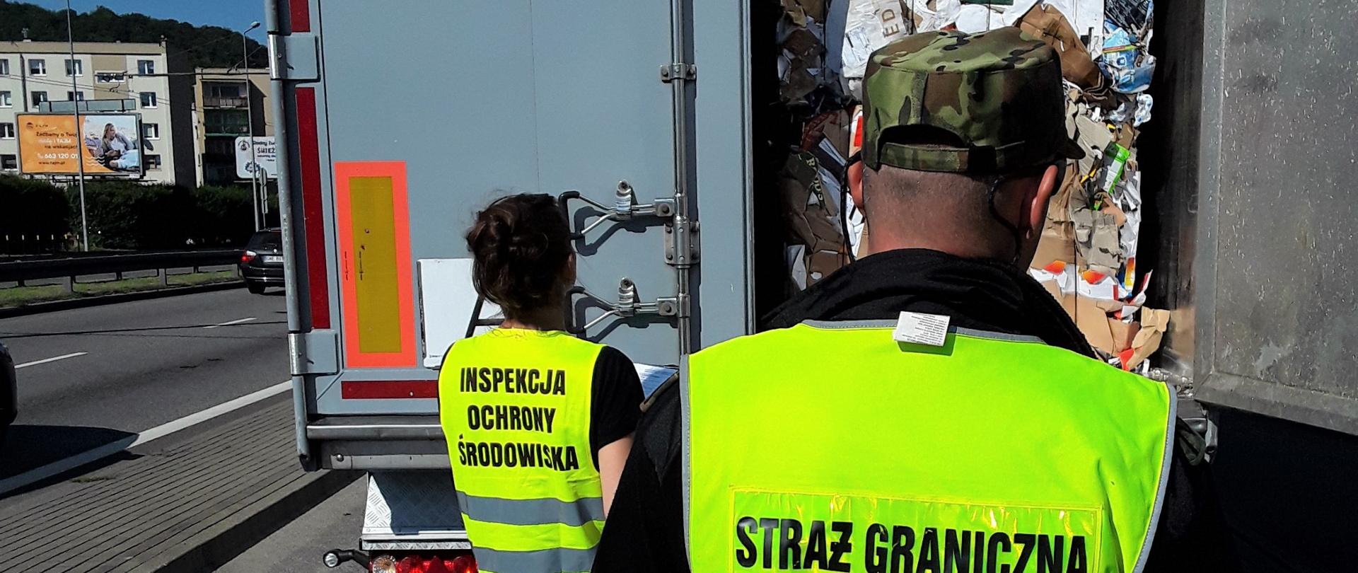 Inspektor WIOŚ w Gdańsku wraz z funkcjonariuszem Straży Granicznej kontrolują strefę załadunkową pojazdu przewożącego odpady.