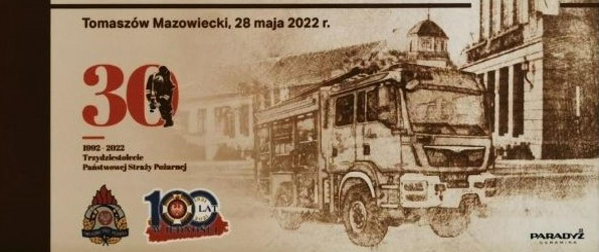 Zdjęcie przedstawia pamiątkowy obraz z napisem Wojewódzkie Obchody Dnia Strażaka 2022 Tomaszów Mazowiecki, 28 maja 2022 r. Pod napisem widoczne logo trzydziestolecia PSP oraz logo PSP. Z prawej strony grafika pojazdu gaśniczego na tle budynku. 