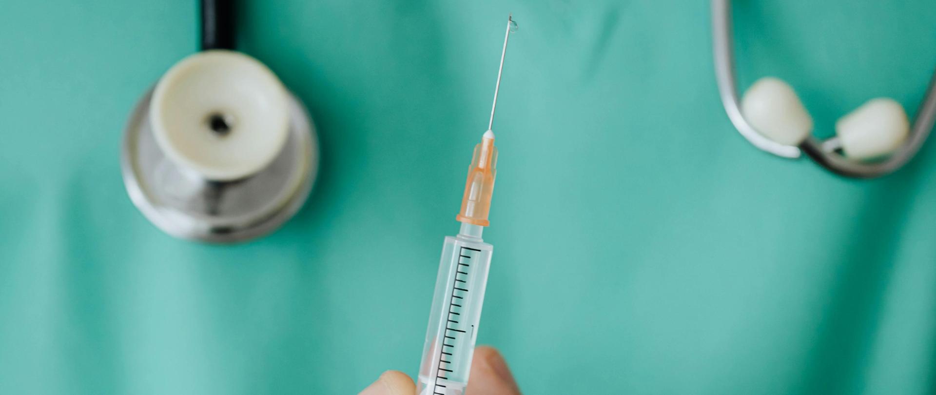 Zdjęcie przedstawia lekarza trzymającego strzykawkę.