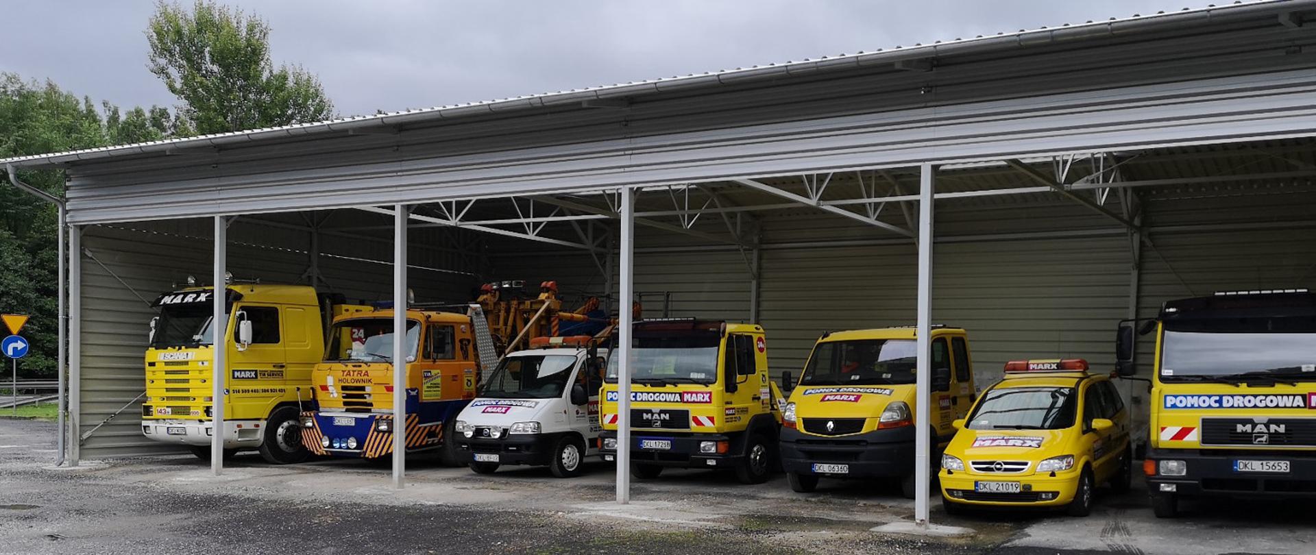 Flota samochodowa pod blaszanym zadaszeniem.