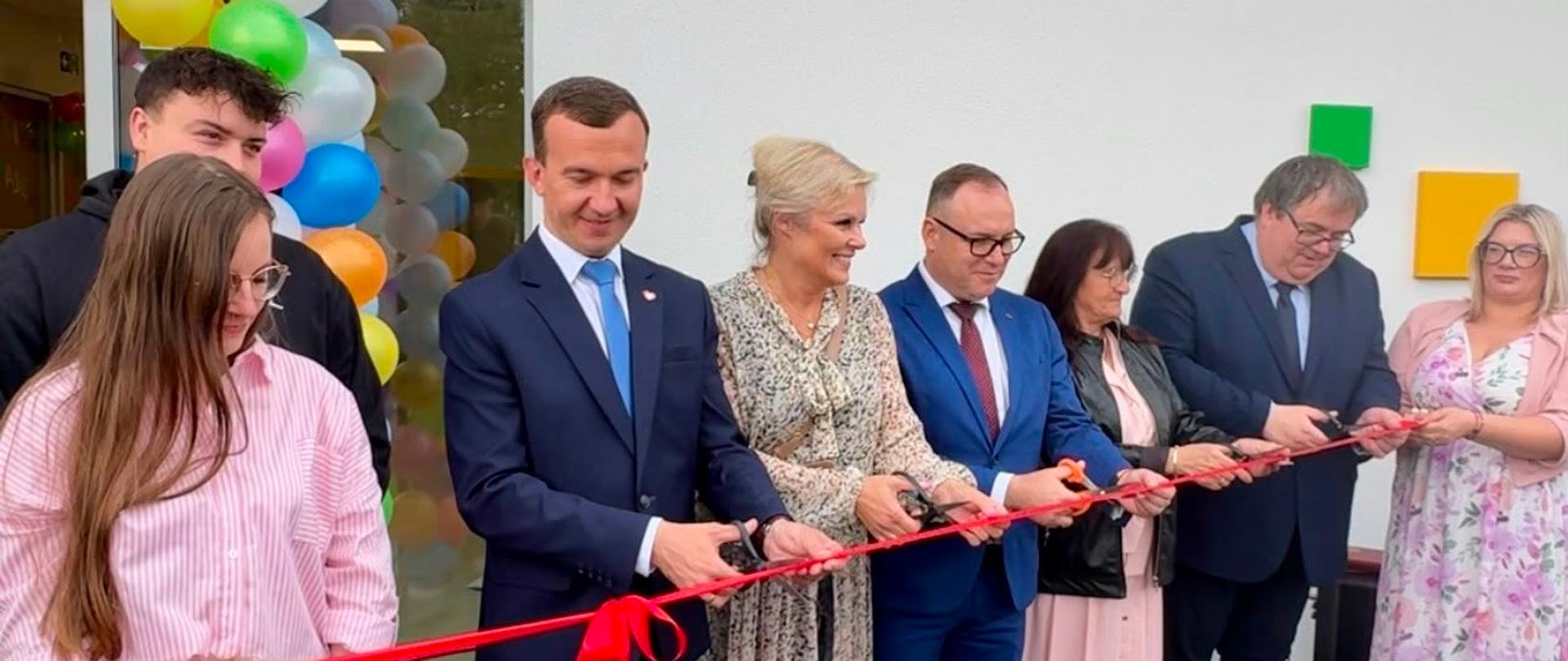 Kilka osób przecina wstęgę stojąc przed budynkiem żłobka 