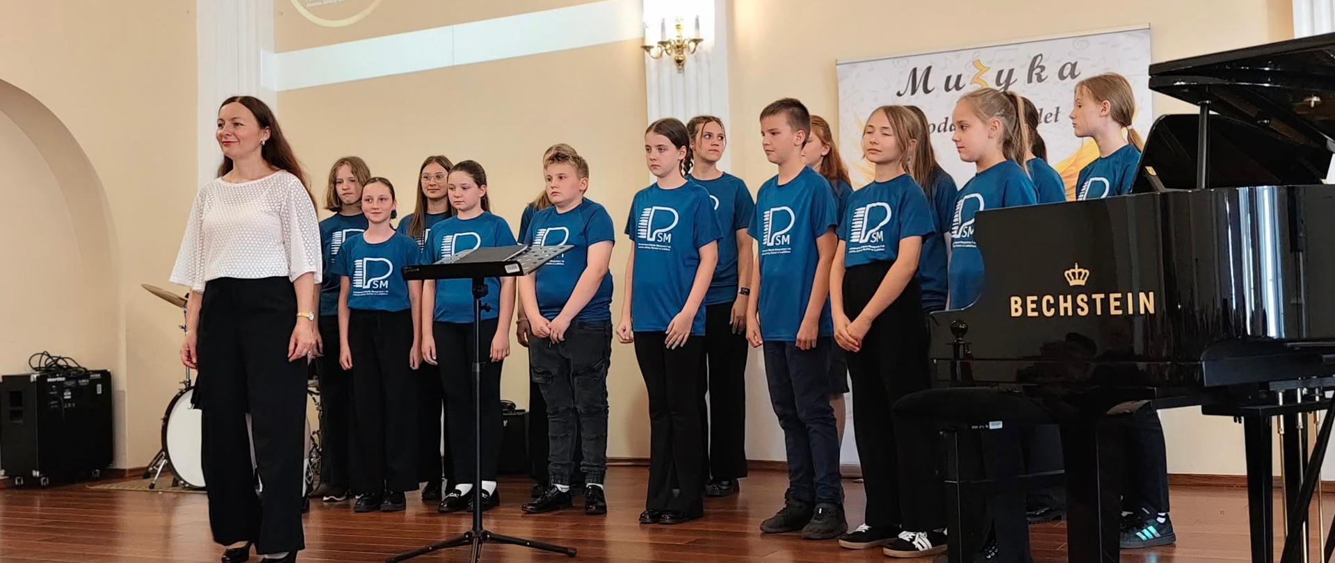 Wykonawcy na scenie w sali koncertowej podczas Koncertu końcoworocznego wpisującego się w szmaragdowy Jubileusz lublinieckiej szkoły muzycznej